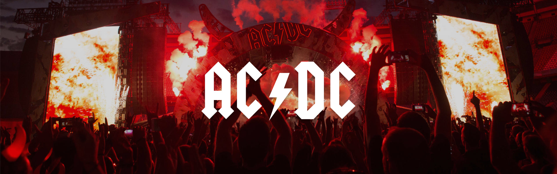 AC/DC concert stage with pyrotechnics and crowd in silhouette, featuring the iconic AC/DC logo in the center.